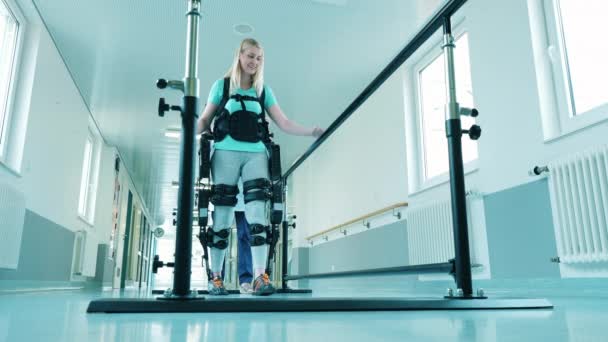 A lady is learning to walk in the exosuit with medical help — Stock Video