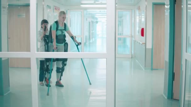 Jeune femme marche dans l'exocostume avec l'aide des médecins — Video