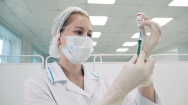 Yüz maskeli doktor şırıngayı dolduruyor.