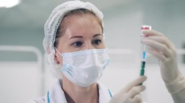 Bir doktor şırıngayı ilaçla dolduruyor.