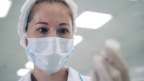 La doctora con mascarilla está mirando una tina de medicinas. — Vídeo de stock