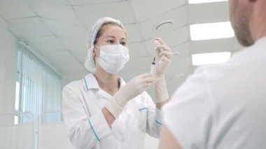 Bir doktor aşıdan önce bir şırınga hazırlıyor.