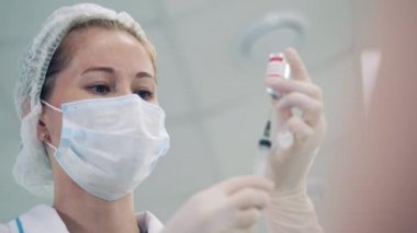 Kadın doktor şırıngayı aşıyla dolduruyor.