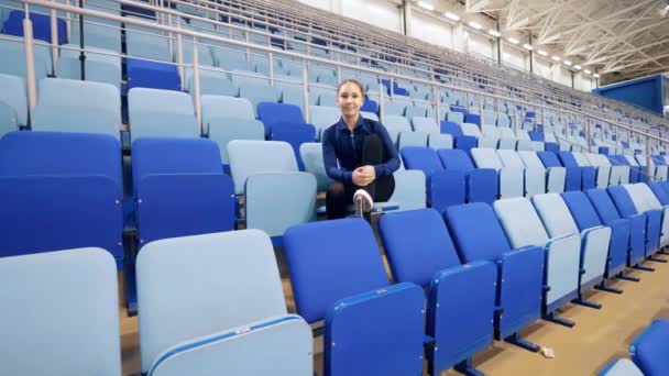 Jovem está sorrindo nos assentos da pista de patinação — Vídeo de Stock