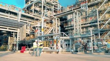 Petrol rafinerisinde iki işçi yürüyor.