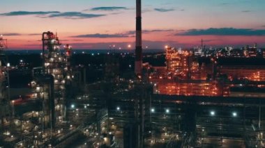 Petrol rafinerisinin, gün batımında elektrikli ışıkları olan binaları.