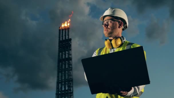 Trabalhador masculino com um laptop perto dos tubos da refinaria de petróleo — Vídeo de Stock
