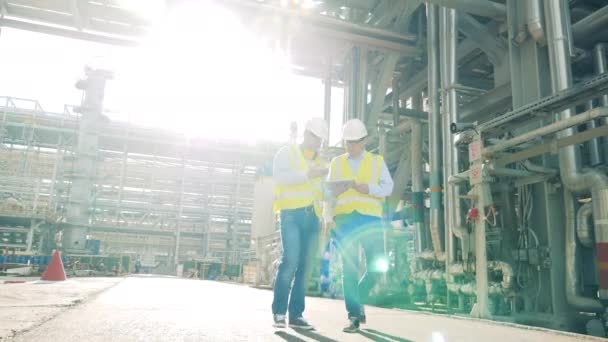 石油精製所を歩いている二人の労働者 — ストック動画