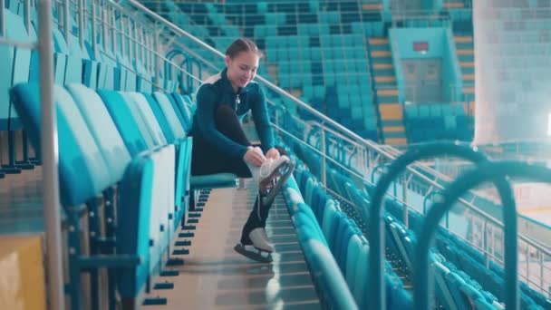 Усміхнена дівчина розправляє ковзани на спортивній арені — стокове відео
