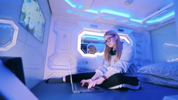 Teenage girl is using her laptop inside of a capsule guest room — Stock video