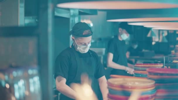 Chefs met gezichtsmaskers werken achter de restaurantbalie. — Stockvideo