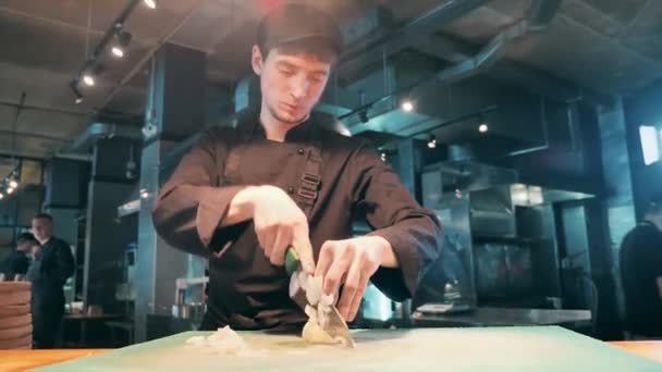 Szef kuchni w mundurze kroi cebulę nożem. — Wideo stockowe
