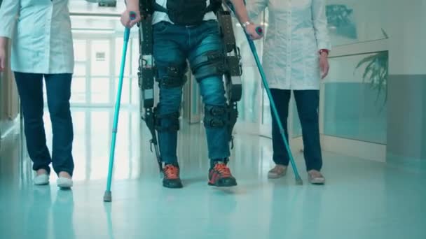 Un patient dans l'exosquelette marche avec des infirmières. — Video