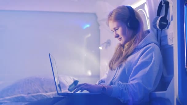 Giovane ragazza sta sorridendo mentre ascolta la musica in un hotel pod — Video Stock