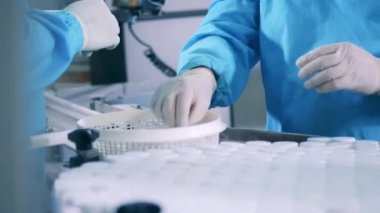 İlaç şişeleri kapatılıyor ve fabrika işçileri tarafından taşınıyor.