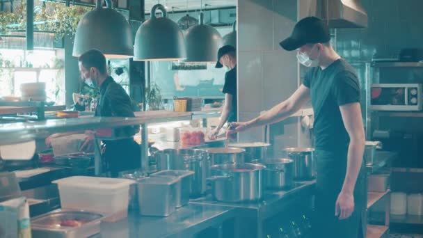Restoran personeli yüz maskesi altında yemek pişiriyor. — Stok video