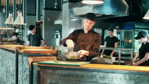 Mężczyzna szef kuchni to przyprawy i rzucanie jedzenie w misce — Wideo stockowe
