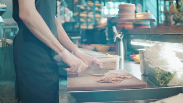 Een kok in handschoenen snijdt gerookt vlees — Stockvideo