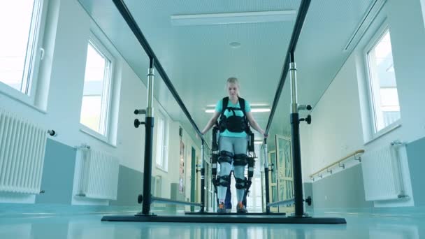 Handicapped woman is walking in the exosuit with medical aid. — Stock Video