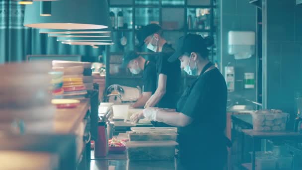 Il personale del ristorante in maschera sta cucinando nella cucina a vista — Video Stock