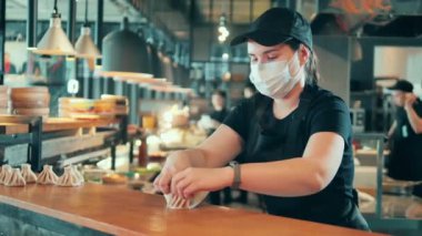 Yüzü maskeli bir aşçı açık mutfakta hamur köftesi yapıyor.