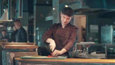 Erkek şef sebze doğrarken gülümsüyor.