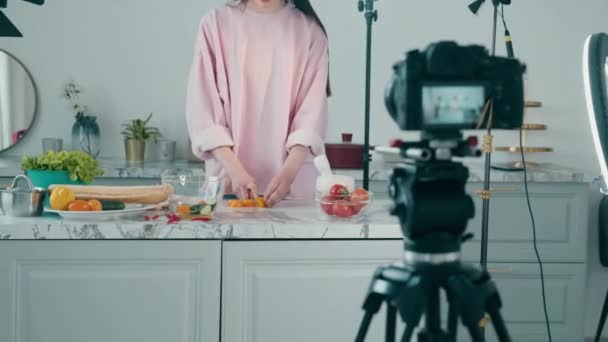 Senhora alegre está cortando legumes para um blog de vídeo — Vídeo de Stock