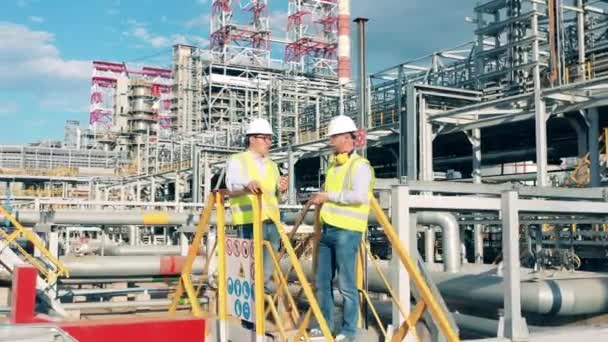 Los empleados de la refinería están hablando al lado de los barriles de la planta — Vídeos de Stock