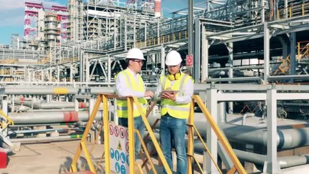 Ingenieure reden inmitten von Ölraffinerie-Bauten — Stockvideo