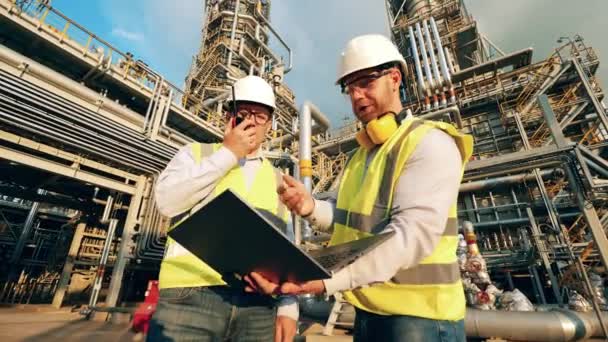 Refinería con dos empleados discutiendo un proyecto — Vídeo de stock