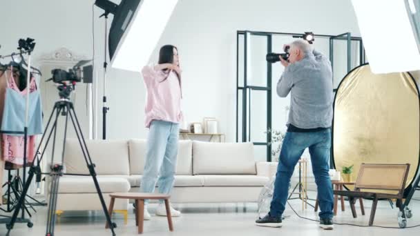 Jovem modelo feminina está tendo uma sessão fotográfica com um fotógrafo — Vídeo de Stock