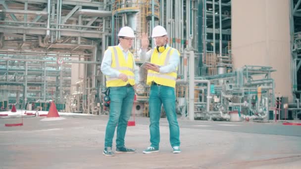 Manliga kollegor diskuterar raffinaderiets lokaler — Stockvideo