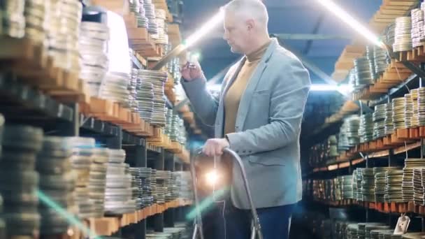Filmexperte inspiziert alte Filmkoffer auf einer Leiter — Stockvideo