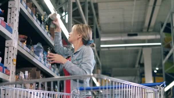 Een vrouw neemt pakjes boodschappen mee uit de winkelschappen. — Stockvideo