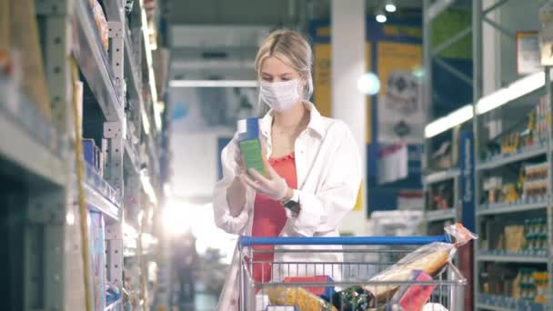 Mulher loira em uma máscara facial está comprando cereais na loja — Vídeo de Stock