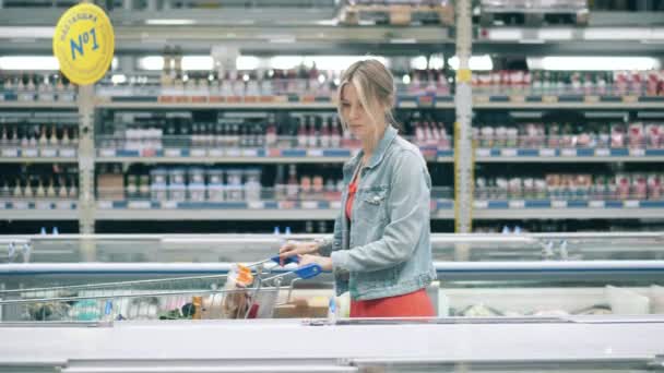 冷凍食品をカートに入れている女性とスーパーマーケット — ストック動画