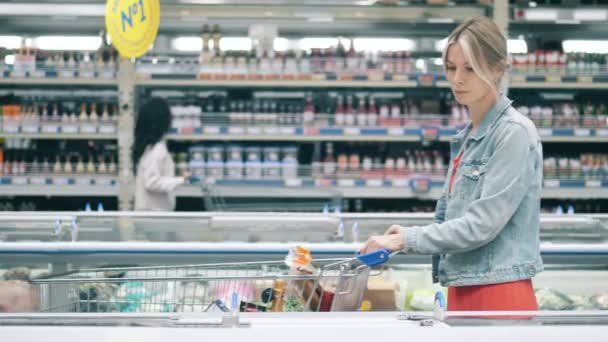 Mulher loira pega um pacote de comida congelada na loja — Vídeo de Stock
