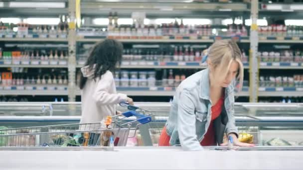 두 여자 가 가게에서 냉동 제품을 줍고 있습니다 — 비디오