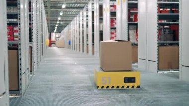 Robot mekanizması depoda bir kutu taşıyor.