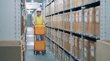 Depo işçisi konteynırlarla bir yük arabası çekiyor.