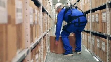 Ergoskeleton 'da bir erkek işçi bir depoya bir kutu koyar.