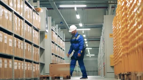 Een pakhuismedewerker stopt een kartonnen doos weg. Ingenieur draagt exoskelet, exospak. — Stockvideo