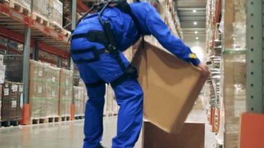 Dış iskelet, dış giysi, robot teknolojisi konsepti. Ergoskeleton 'daki erkek işçi depoda kutu saklıyor.