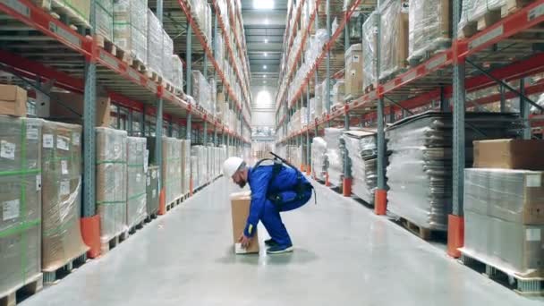 Een pakhuismedewerker pakt een doos en draagt hem weg. Exoskelet, exosuit, robottechnologie concept. — Stockvideo