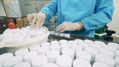 Fabrika işçisi ilaç tüplerini taşıyıcıdan geçiriyor.