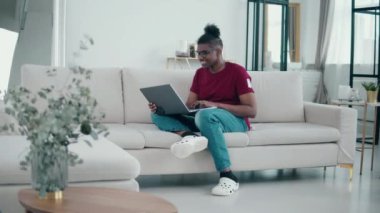 Afro-Amerikalı adam oturma odasında internetten konuşuyor.
