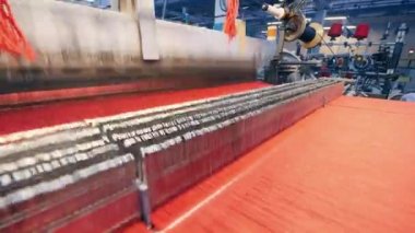 İçinden kırmızı iplikler geçen dokuma mekanizması.