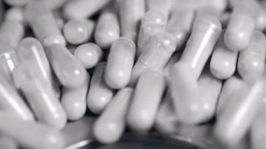 Pudralanmış ilaçlı kapsüller bir deliğe düşüyor.