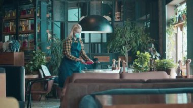 Maskeli garson masaya tabak koyuyor.