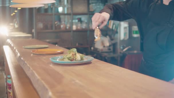 Pracownik restauracji kładzie krewetki na talerzu sałatki. — Wideo stockowe